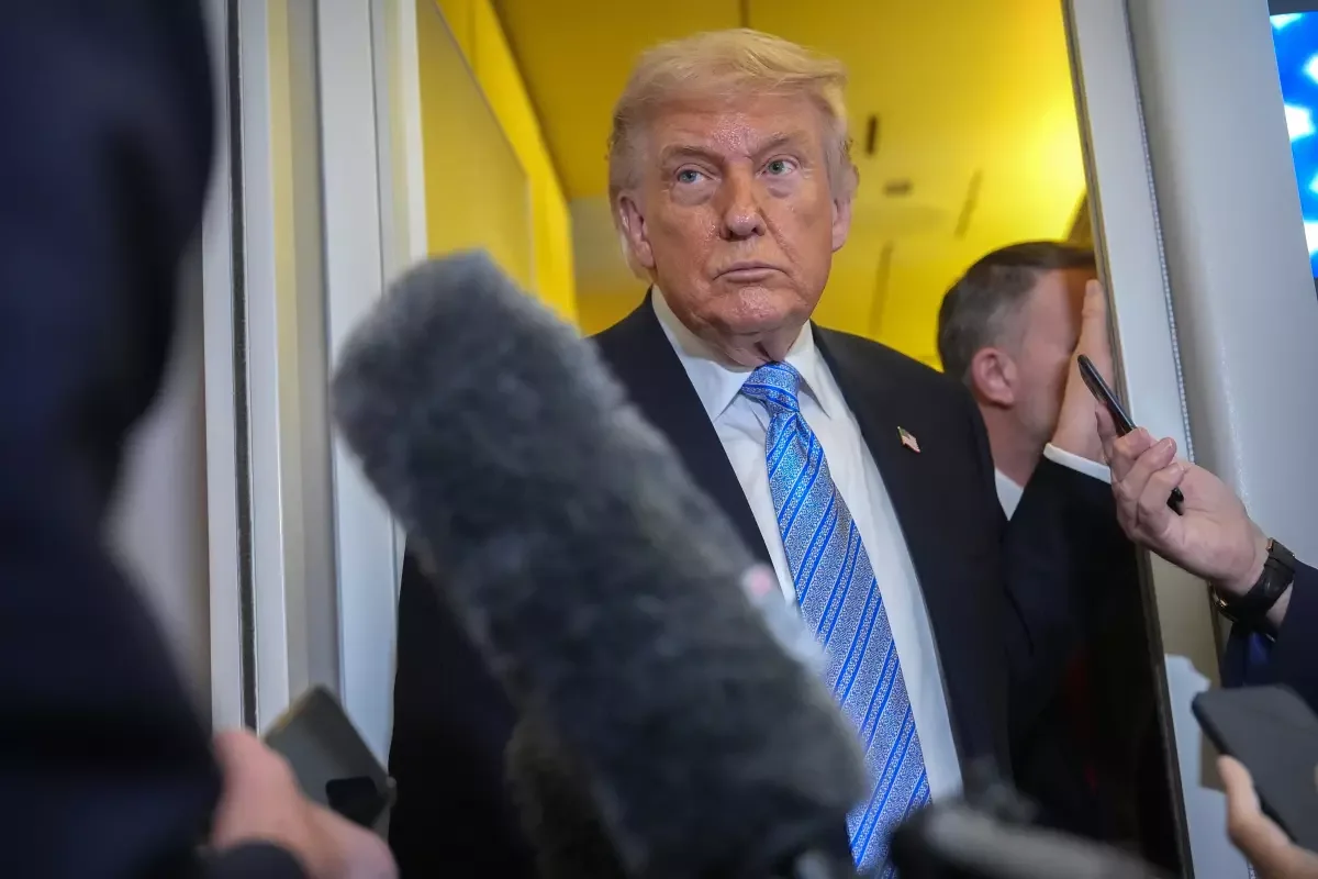 President Trump speaks to reporters aboard Air Force One on Friday as he returns from China. (Mark Schiefelbein / Associated Press)