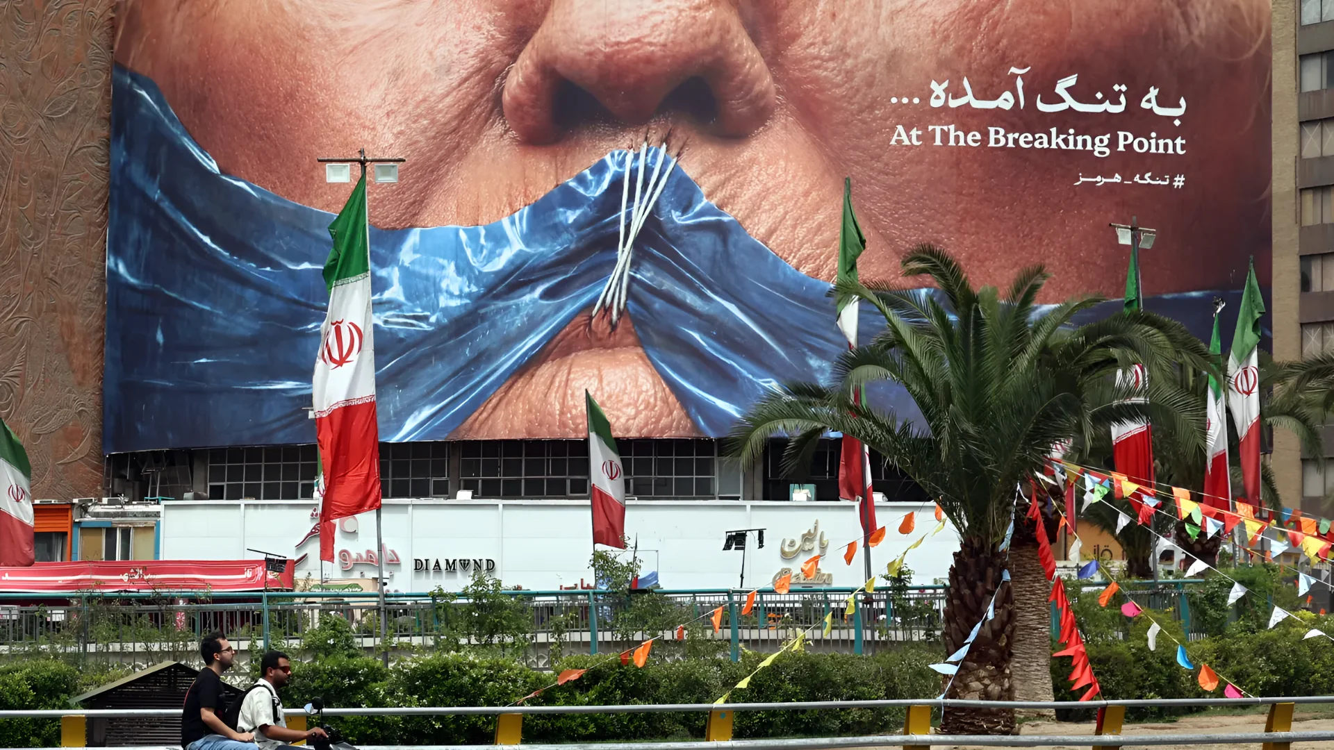 Iranians drive past a billboard featuring US President Donald Trump and the Strait of Hormuz, erected on Valiasr Square in Tehran May 28, 2026. - | Afp | Getty Images