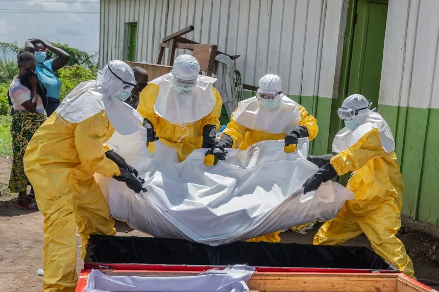 Red Cross workers carry the body of a person who died of Ebola into a coffin at a health center in Rwampara, Congo, on May 20. Moses Sawasawa/AP