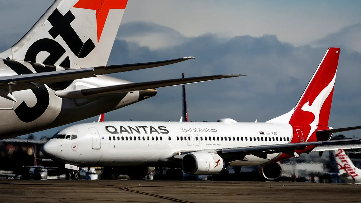 A Jetstar Airlines Boeing 787-8 plane and a Qantas Airways Boeing 737-800 plane line up with other aircraft on the runway at Sydney International Airport on a windy day in Sydney on June 25, 2025.  (DAVID GRAY/AFP via Getty Images / Getty Images)
