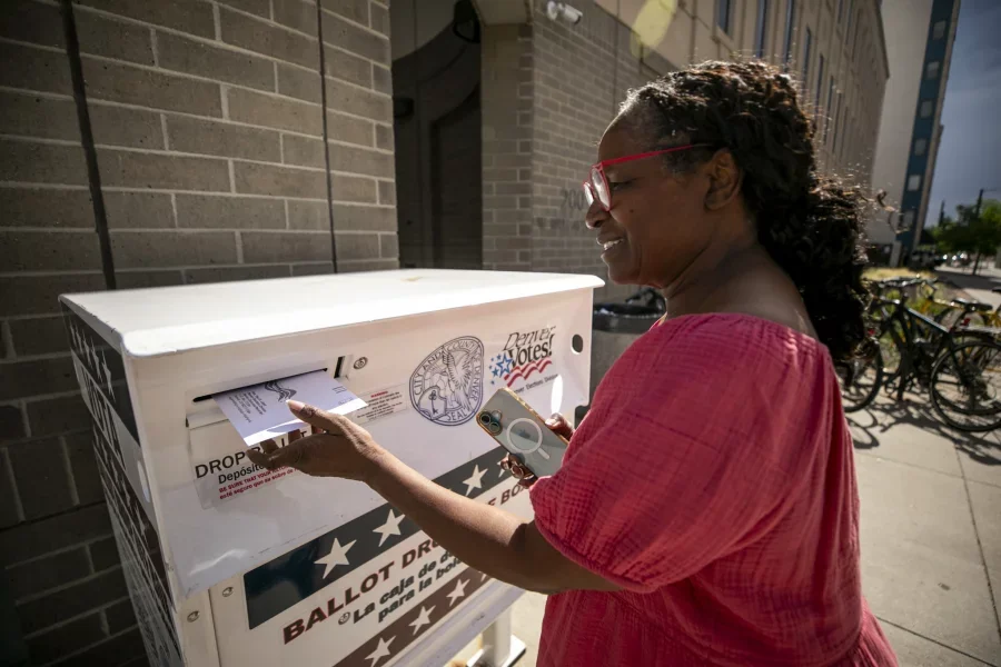 Darlene Jenkins slides her parents' ballots into a dropbox in Denver during the Colorado primary elections Tuesday. Kevin J. Beaty/Denverite