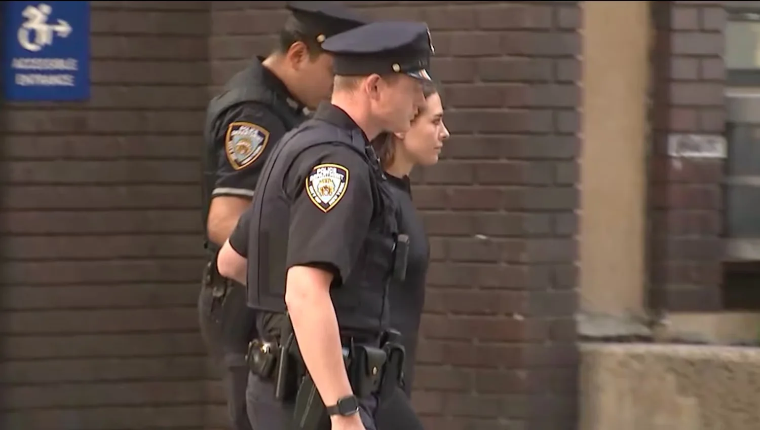 Angela Nikolau is seen being escorted out of a Manhattan police station, July 1, 2026. WABC
