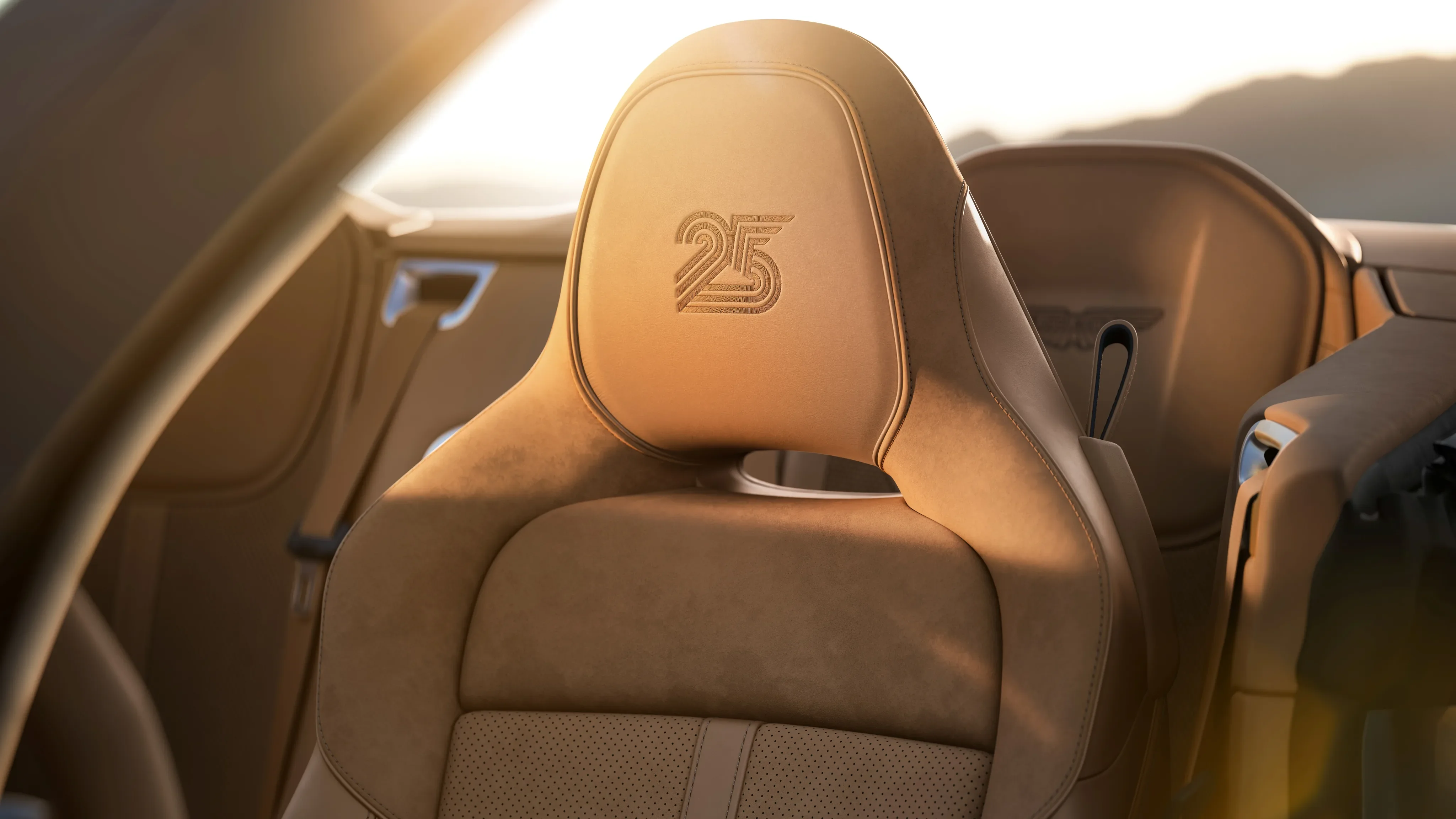 Tan leather interior seat of an Aston Martin Vanquish with an embossed 25 logo on the headrest.