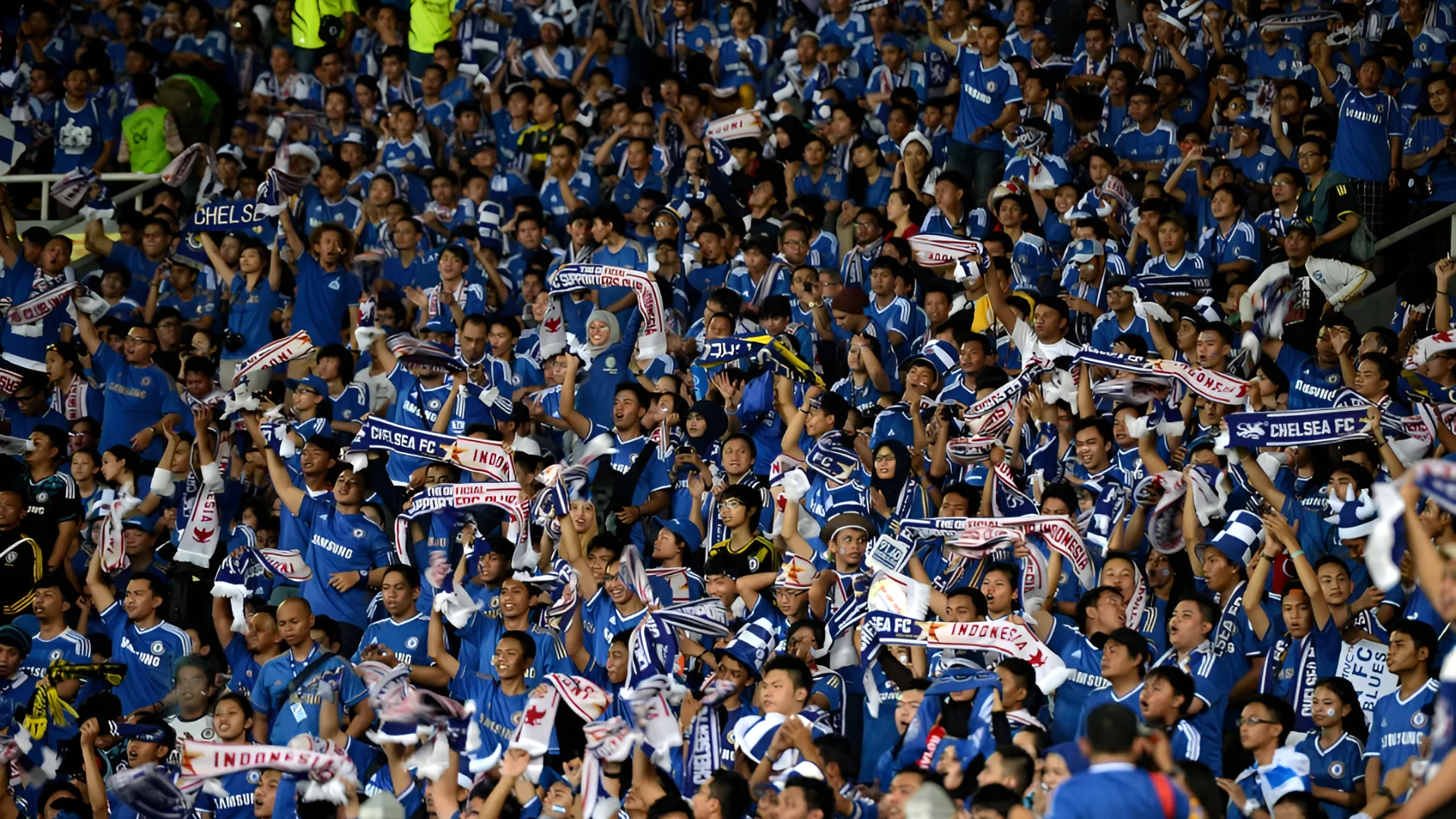 Chelsea fans cheer on their side from the stands with scarfs and signs (Photo by Darren Walsh/Chelsea FC via Getty Image