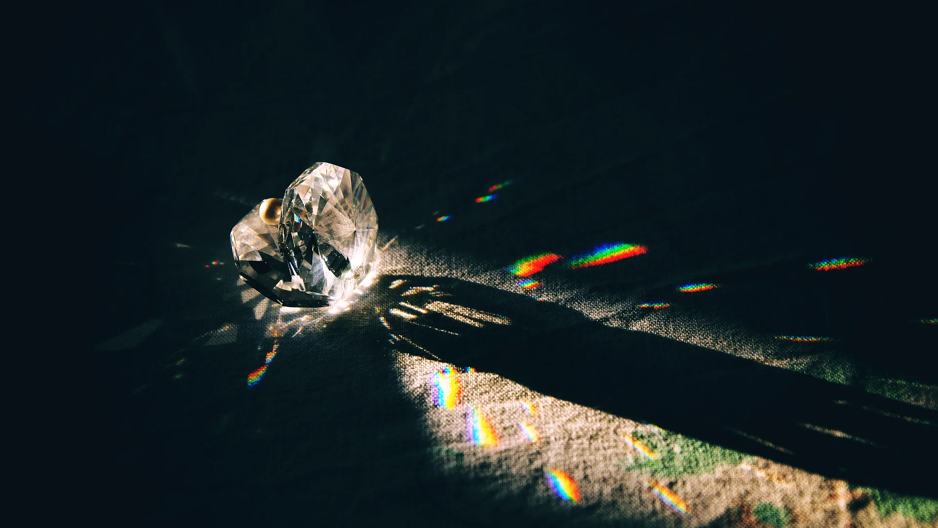 A diamond-shaped crystal casting rainbow reflections under dramatic lighting. Photo: Andrea Aliverti.